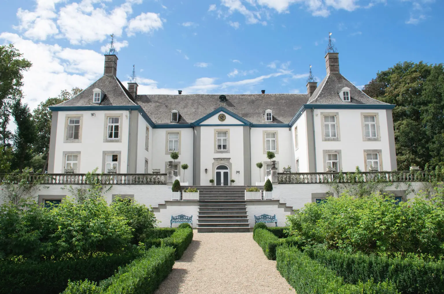 Großes symmetrisches weiße Villa mit grauem Dach und englischem Garten