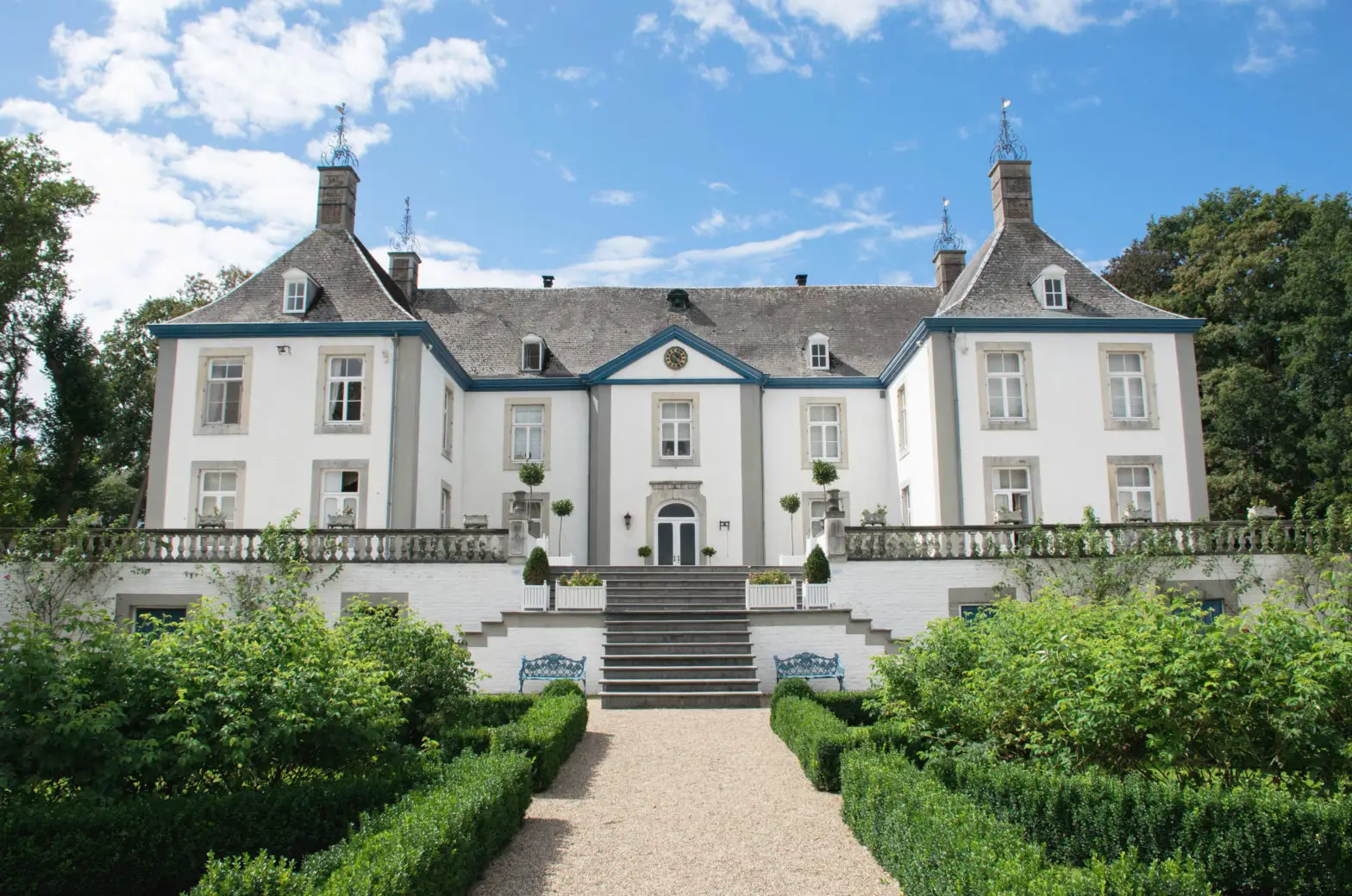 Großes symmetrisches weiße Villa mit grauem Dach und englischem Garten
