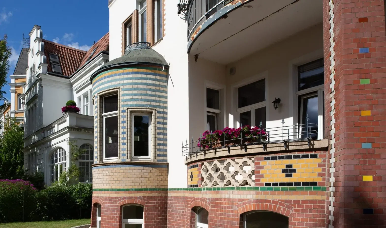 Fassade eines historischen Wohnhauses mit buntem Klinker und verzierten Balkonen.