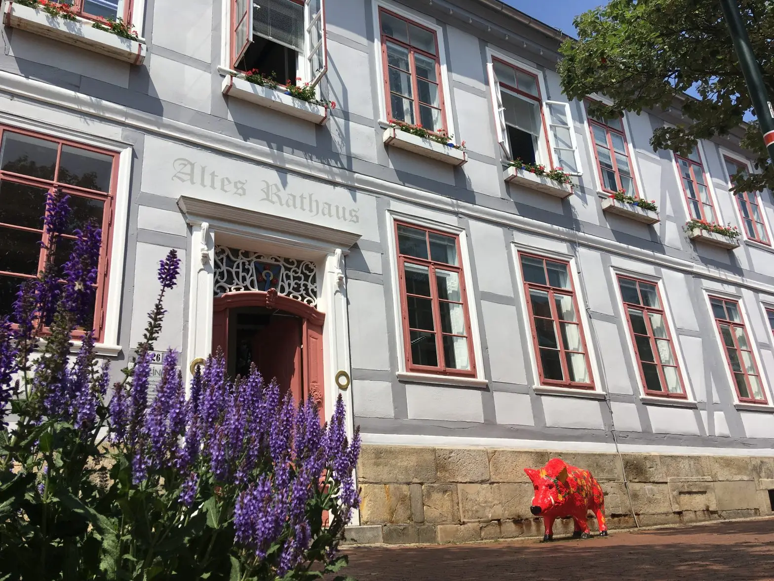 Altes Rathaus in Springe mit roter Kunstfigur und Blumenbeet im Vordergrund