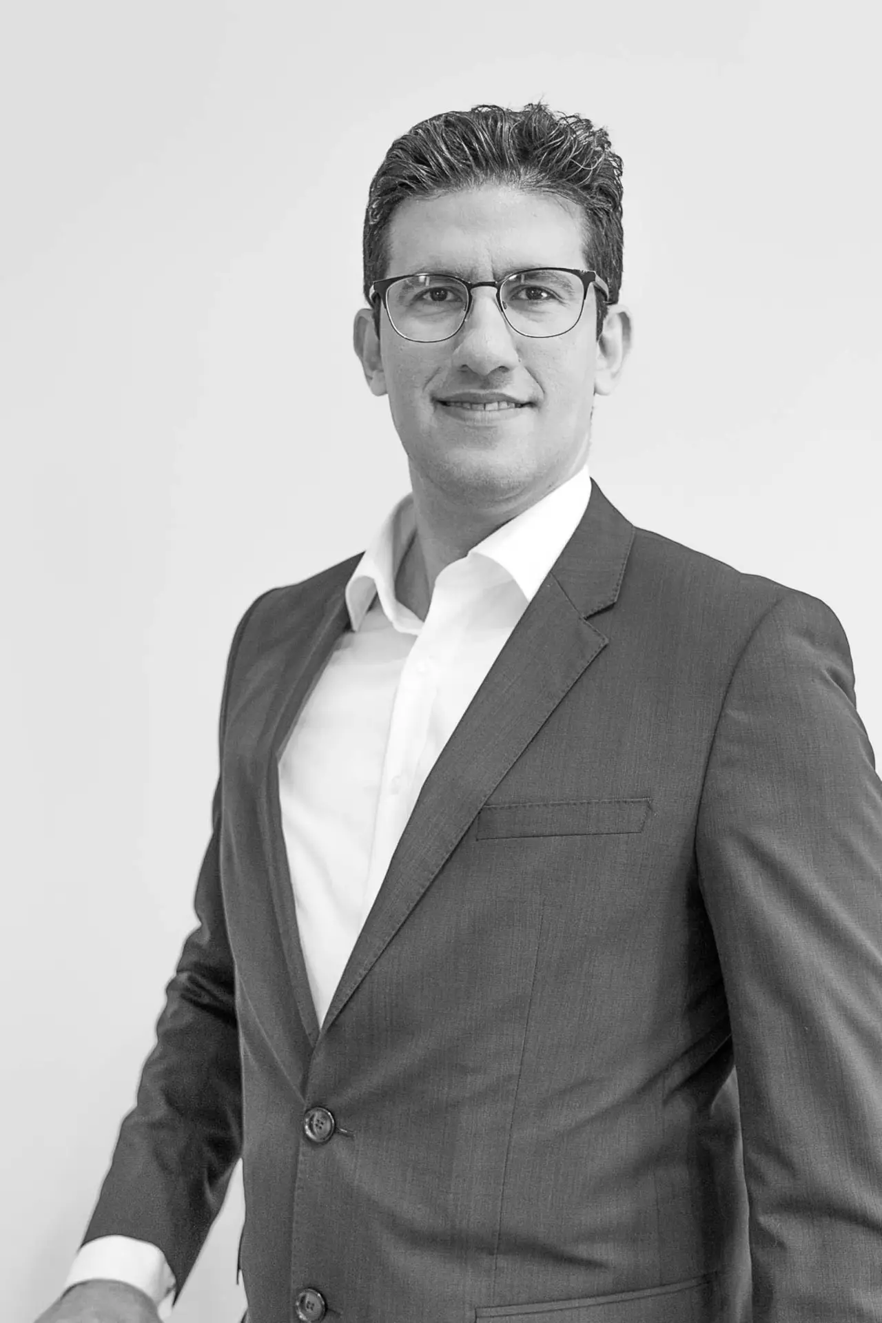 Porträt eines lächelnden Mannes im Anzug, vor neutralem Hintergrund – Herr Omid Ghotratabadi von Sotheby’s International Realty.