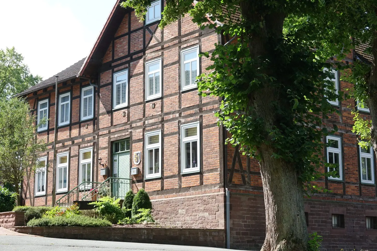 Fachwerkhaus der Gemeindeverwaltung Holzminden mit grüner Eingangstreppe und altem Baumbestand
