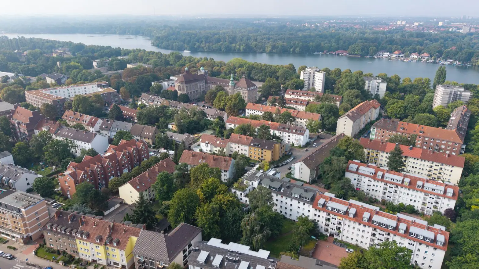 Luftaufnahme der Südstadt von Hannover mit roten Dächern und Fluss im Hintergrund.
